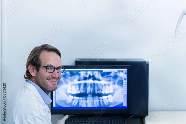 Fototapeta Computer workstation displaying panoramic dental X-ray in exam room, with lamp arm and keyboard