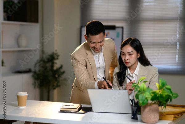 Fototapeta Business colleagues working together at laptop, discussing ideas and reviewing project data in an office