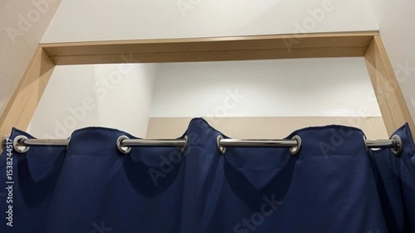 Obraz Changing room. Close-up photo of blue fabric curtain hanging on a shiny metal rod with round wall mounts