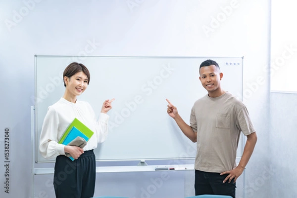 Obraz 教室のホワイトボードを指さす黒人男性と日本人女性