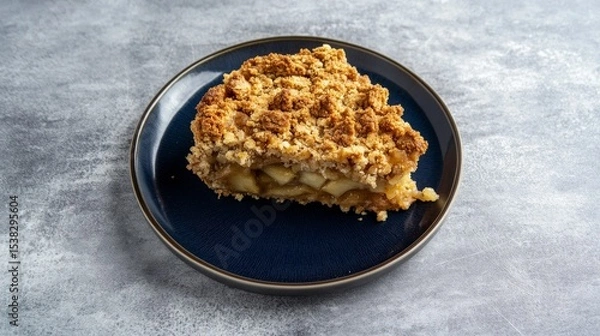 Fototapeta A delectable slice of apple crumble, showcasing its irresistible crumbly topping and the juicy, tender apples within. A perfect autumn dessert, this homemade treat is both comforting and satisfying.