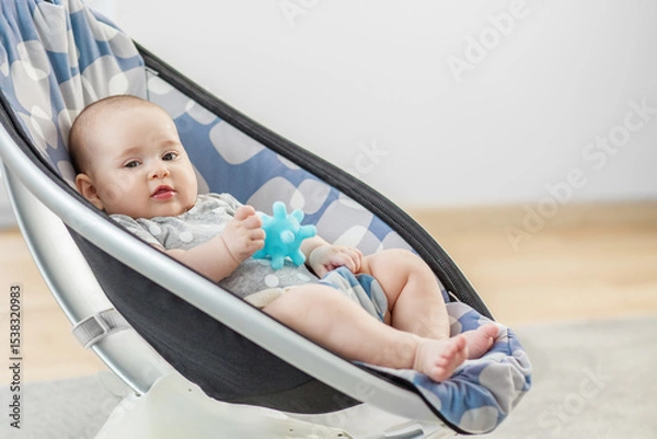 Fototapeta Baby resting in rocker with blue teether