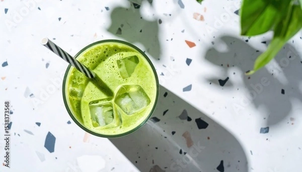 Obraz Glass of iced matcha latte with straw casting shadow on terrazzo surface, top view aesthetic drink trend