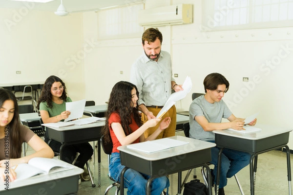 Obraz Teacher helping high school student with exam in classroom