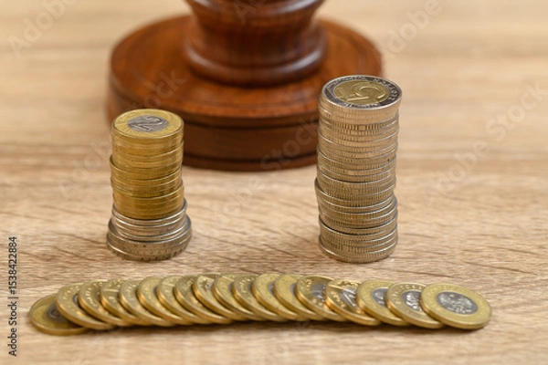 Obraz Close-up of a judge's gavel standing behind a pile of metal coins, a symbol of economic justice