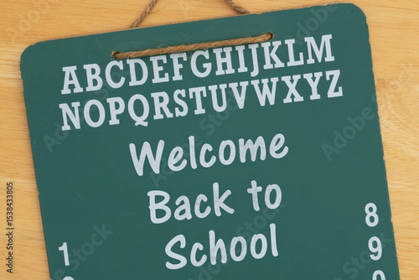 Obraz Welcome Back to School on a green chalkboard on a wood desk