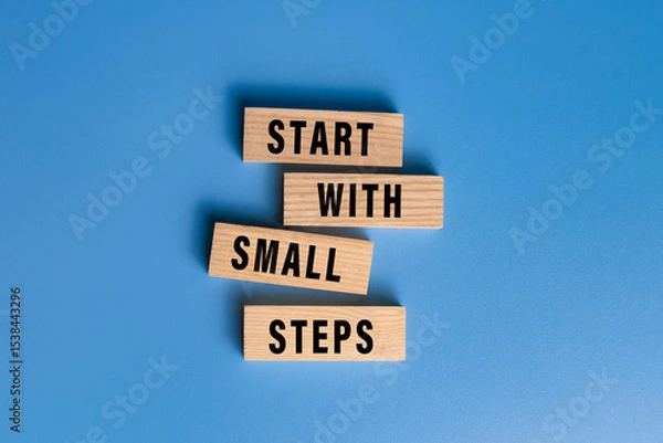 Fototapeta start with small steps words text on wooden blocks isolated on blue background
