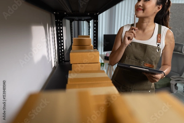 Obraz a female employee is checking parcel boxes in a warehouse, a warehouse manager is counting parcel boxes on shelves, a small online business owner is in a storage room