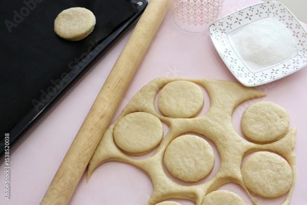 Fototapeta Cutting cookies from raw dough on table.
The raw cookies lying on a kitchen table. Horizontal  shot.