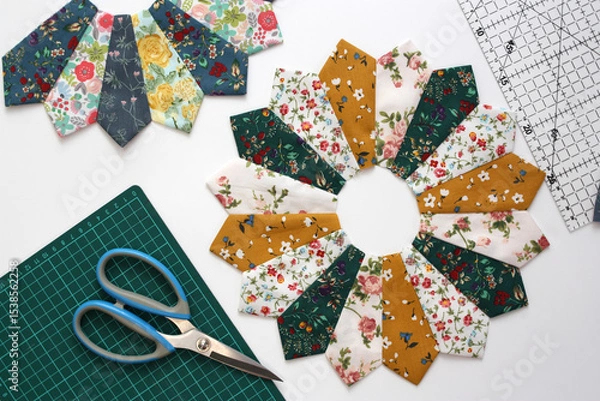 Fototapeta On a white background, fabric blocks for a handmade patchwork quilt. The blocks are called the Dresden Plate. Multi-colored cotton fabrics, scissors . Concept modeling and sewing as a hobby.