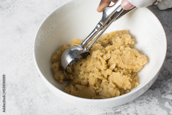 Obraz scooping vanilla cookie dough in a white mixing bowl, process of making vanilla cookie dough