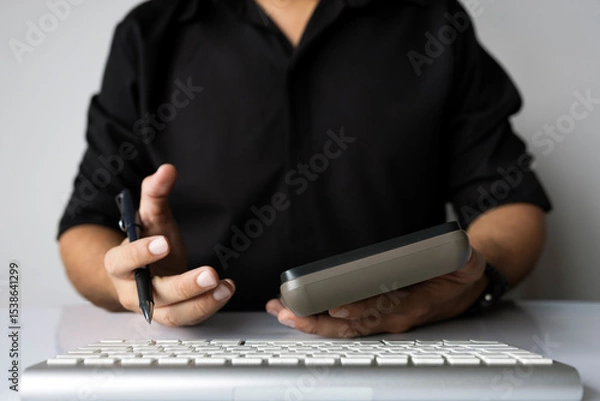 Obraz Man holding calculator and pen for business planning or finance calculation