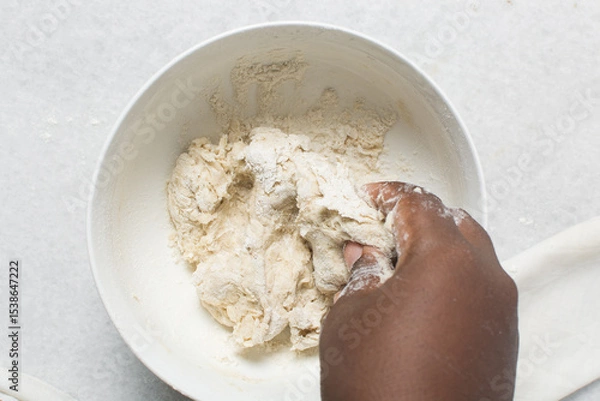 Fototapeta Overhead view of crackers dough being mixed in white bowl, top view of homemade crackers dough being mixed in bowl, process of making crackers