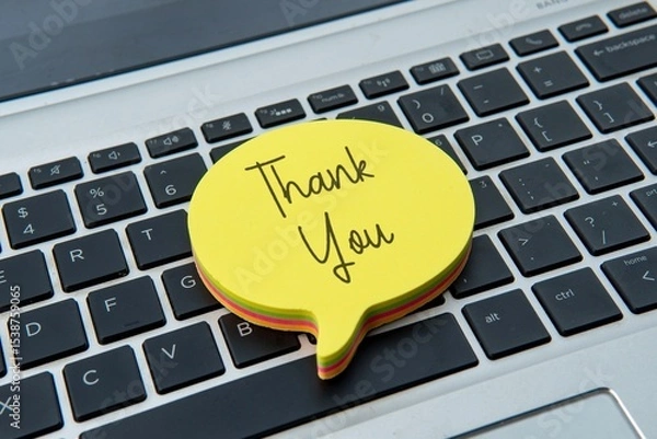 Obraz A sticky note with "Thank You" on top of a laptop keyboard. Gratitude, appreciation, recognition, and positive interaction in a modern workspace.