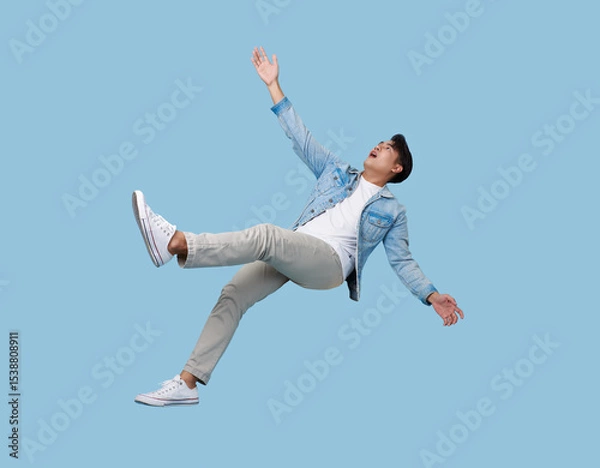 Fototapeta excited asian man relaxing floating in mid-air isolated on blue copy space background.