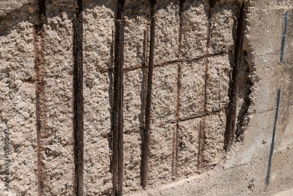 Fototapeta rust and oxidized metal on a building with reinforced concrete structure. facade restoration, corroded iron bars, involves application of anticorrosive on the structural lesions of the retaining wall.