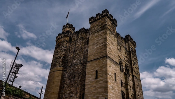 Fototapeta The imposing stone keep of Newcastle Castle stands tall against a backdrop of dramatic clouds, showcasing its historical architecture