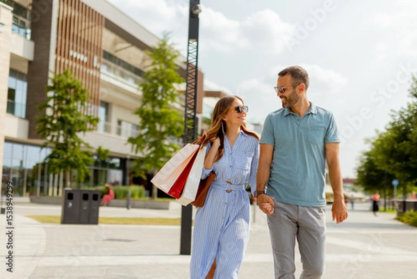Obraz Couple enjoying a sunny day strolling through a vibrant shopping district with colorful storefronts and lush greenery