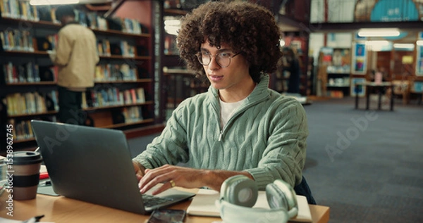 Obraz Student, laptop and typing in library with man for studying, assignment or thesis on college campus. Computer, writing and male person with education, preparation for exam or research for paper