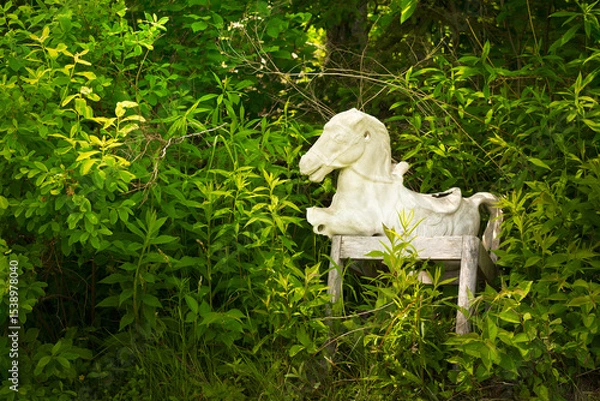 Obraz An old and abandoned rocking horse in thick foliage