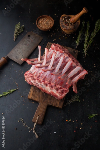 Fototapeta Raw rack of lamb with spices on a cutting board