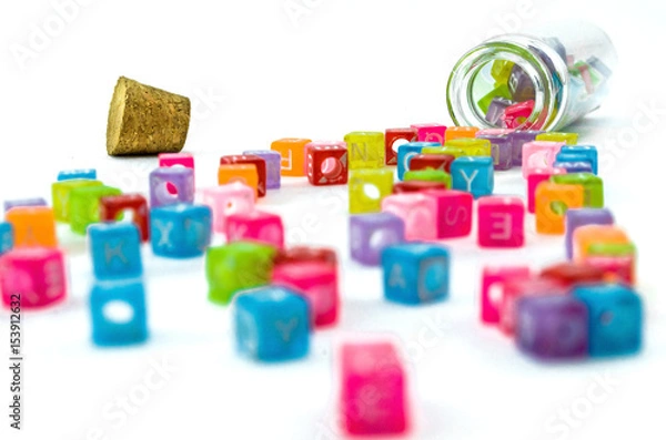 Fototapeta Colourful small cubes with characters random scattered from the vial isolated on white background. Word education concept.