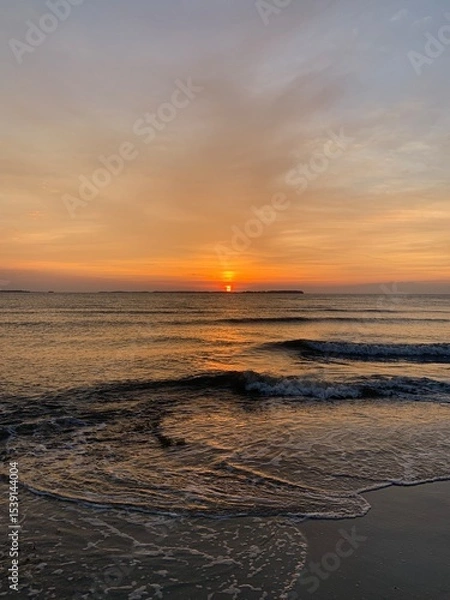 Fototapeta Golden Sunset Over Calm Water with Rays Through Cloud