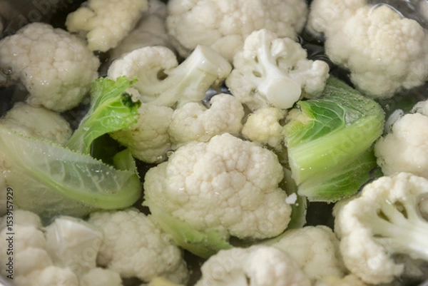 Fototapeta Fresh cauliflower is boiled in a water. The vegetable is divided into florets and boiled