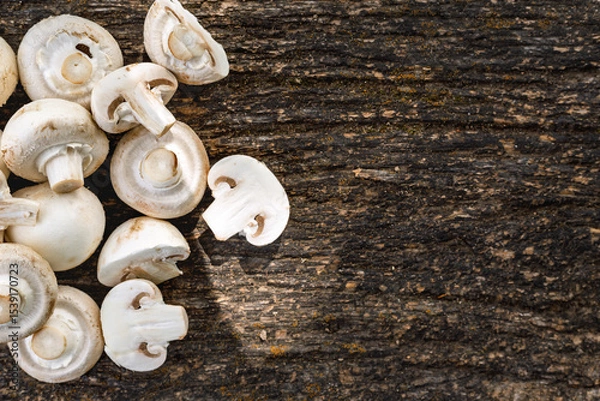 Fototapeta Top view of fresh white mushrooms sliced and whole on rustic dark wooden background with copy space. Organic vegetarian food and cooking ingredient concept