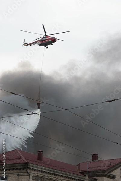 Obraz Another sleepless night in Kyiv. Helicopter extinguishes fire in city. The aftermath of russian drone and missile strikes on residential areas of the city
