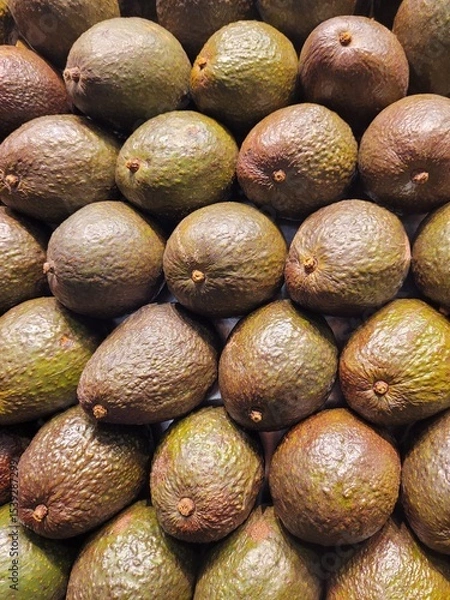Fototapeta Stacked avocados forming a fresh and vibrant background.The image highlights the natural texture and earthy tones of the fruit, ideal for healthy food concepts, packaging design, or organic lifestyle.
