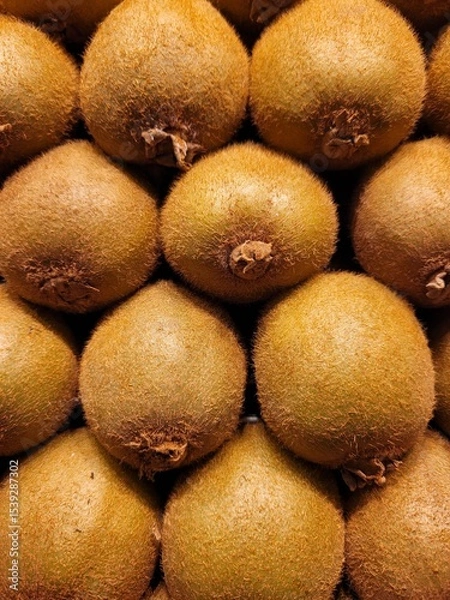 Fototapeta Stacked kiwis forming a fresh and vibrant background. The image highlights the natural texture and earthy tones of the fruit, ideal for healthy food concepts, packaging design, or organic lifestyle.