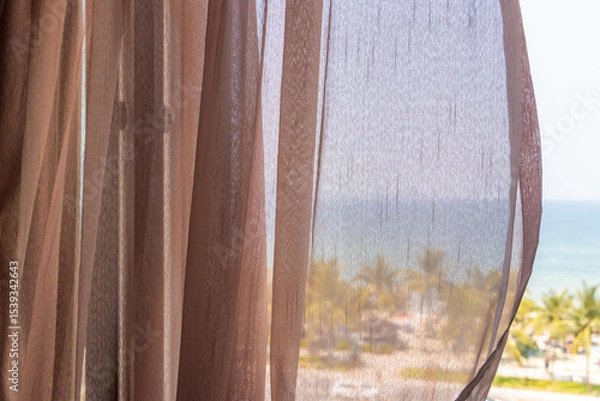 Obraz Soft transparent curtains gently blowing beside a window with a tropical view of the sea beach with palm trees