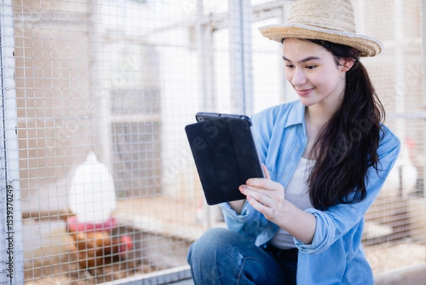 Fototapeta Young scientist in farm setting uses tablet to assist with agricultural research as part of dedicated team, capturing data and observing animals with focused and happy expression