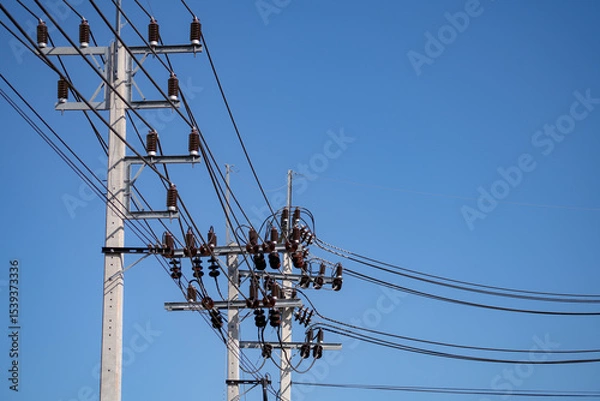 Obraz High voltage transmission pole with electrical equipment including cables and insulators on concrete structure under clear blue sky showing modern power grid infrastructure in wind energy facility