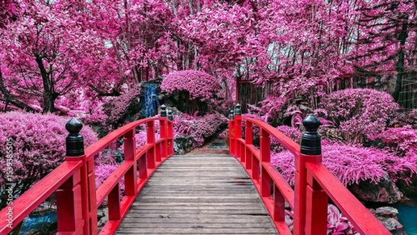 Obraz Vibrant red bridge crosses serene stream in garden filled with lush pink foliage, creating dreamlike atmosphere
