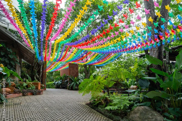 Obraz Colorful paper birds hang in vibrant outdoor garden, creating festive and lively atmosphere