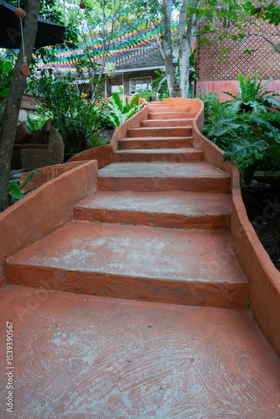 Obraz Curved orange concrete steps lead through lush greenery in garden setting