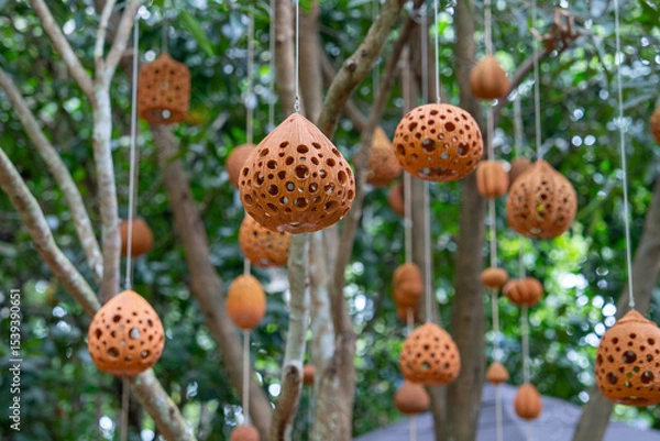 Obraz Hanging clay lanterns with intricate patterns sway gently among lush green trees