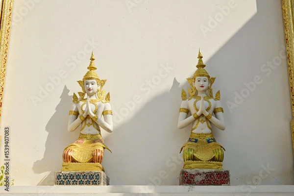 Obraz A Thai art statue of an angel in a seated position with hands clasped together, decorated on the side wall of the chapel in the temple area at Wat Den Sali Si Mueang Kaen temple. At Cheng Mai,Thailand