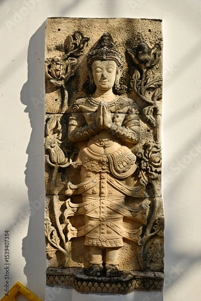 Obraz A Thai art statue of an angel in a standing position with hands together, decorated on the side wall of the chapel in the temple area at Wat Den Sali Si Mueang Kaen temple. at Cheng Mai in Thailand.