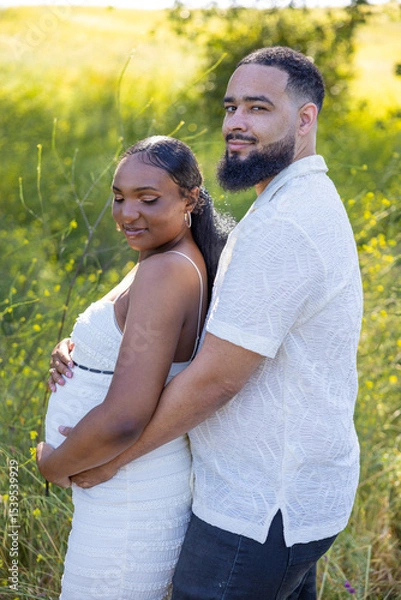 Obraz On a beautiful, sunny summer day, a loving African American couple enjoys an intimate and affectionate moment outdoors, joyfully celebrating their exciting pregnancy in a stunning natural setting