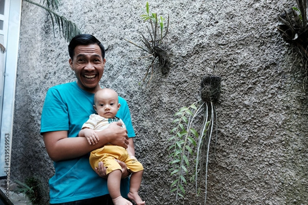 Obraz A Southeast asian father playing with baby boy in the home garden, doing everything together. Happy family 