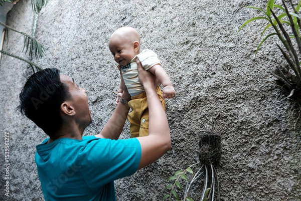 Obraz A Southeast asian father playing with baby boy in the home garden, doing everything together. Happy family 