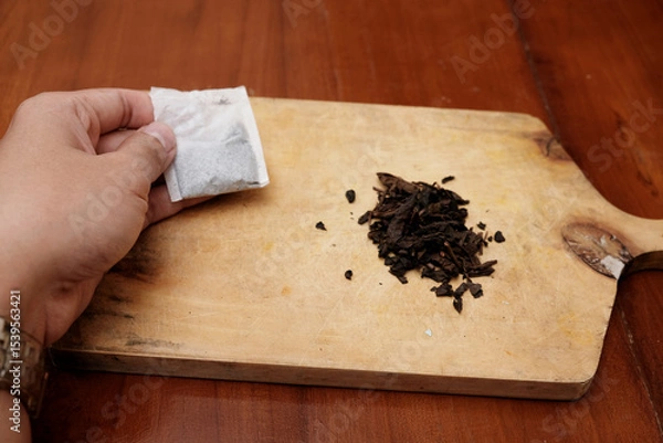 Obraz Closeup of hand man holding Tea bags and a bunch of loose tea in the wooden board. A quick and convenient way to brew tea.