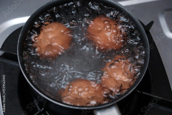 Obraz A pan with some boiling eggs on a stove. Chicken eggs in boiling water. Cooking process.