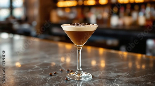 Fototapeta A Martini glass filled with espresso martini sits marble bar counter, garnished with coffee beans. background is softly blurred, creating cozy