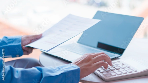 Fototapeta Financial management and expense calculation concept, professional analyzing financial reports and using calculator and laptop for budgeting.