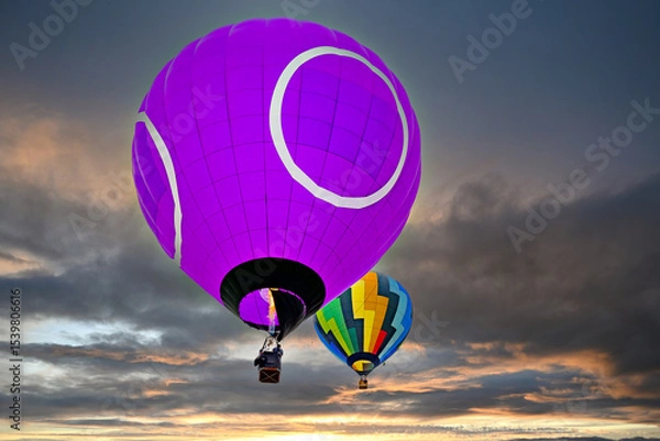 Obraz Colorful hot air balloon flying under orange sunset sky