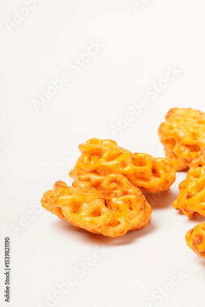 Fototapeta A pile of spicy Indonesian crackers or Kerupuk with spiral twists, coated in red-orange chili powder and rich spices. Bold, flavorful, and appetite-boosting. Photographed against a white background.